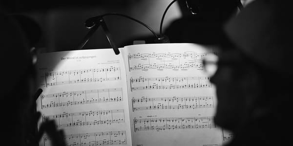 Beleuchtetes Notenheft mit Dirigent im Hintergrund